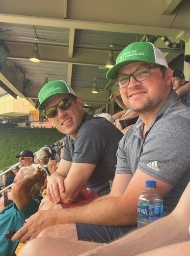 Photograph of Perspective 6 Group financial advisors, Matt Nelson and Jacob LaRue in matching green Focus Financial hats.