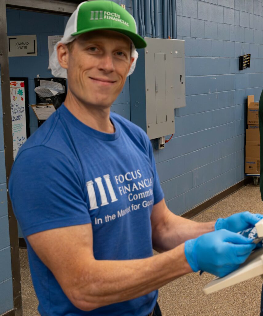 Financial advisor, Matthew Nelson, smiling as he packs meals at Focus Financials' client volunteer event at Feed My Starving Children in Coon Rapids, MN.
