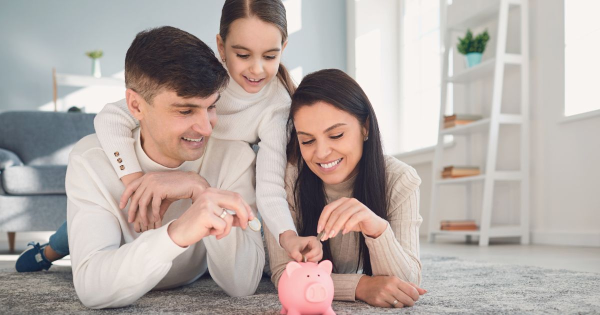 Photograph of a family all putting money in the piggy bank to give visual how important it is to use strategies to maximize your 401(k) as soon as possible.